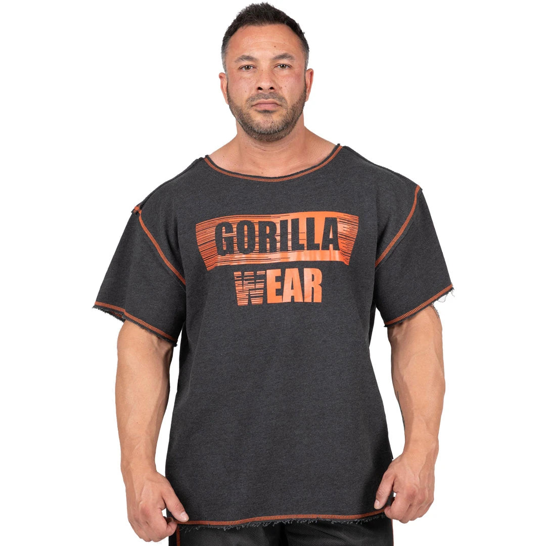 Mørkegrå Gorilla Wear Wallace Workout Top Grey/Orange, en oversized trenings-t-skjorte med oransje logo og rå kanter.