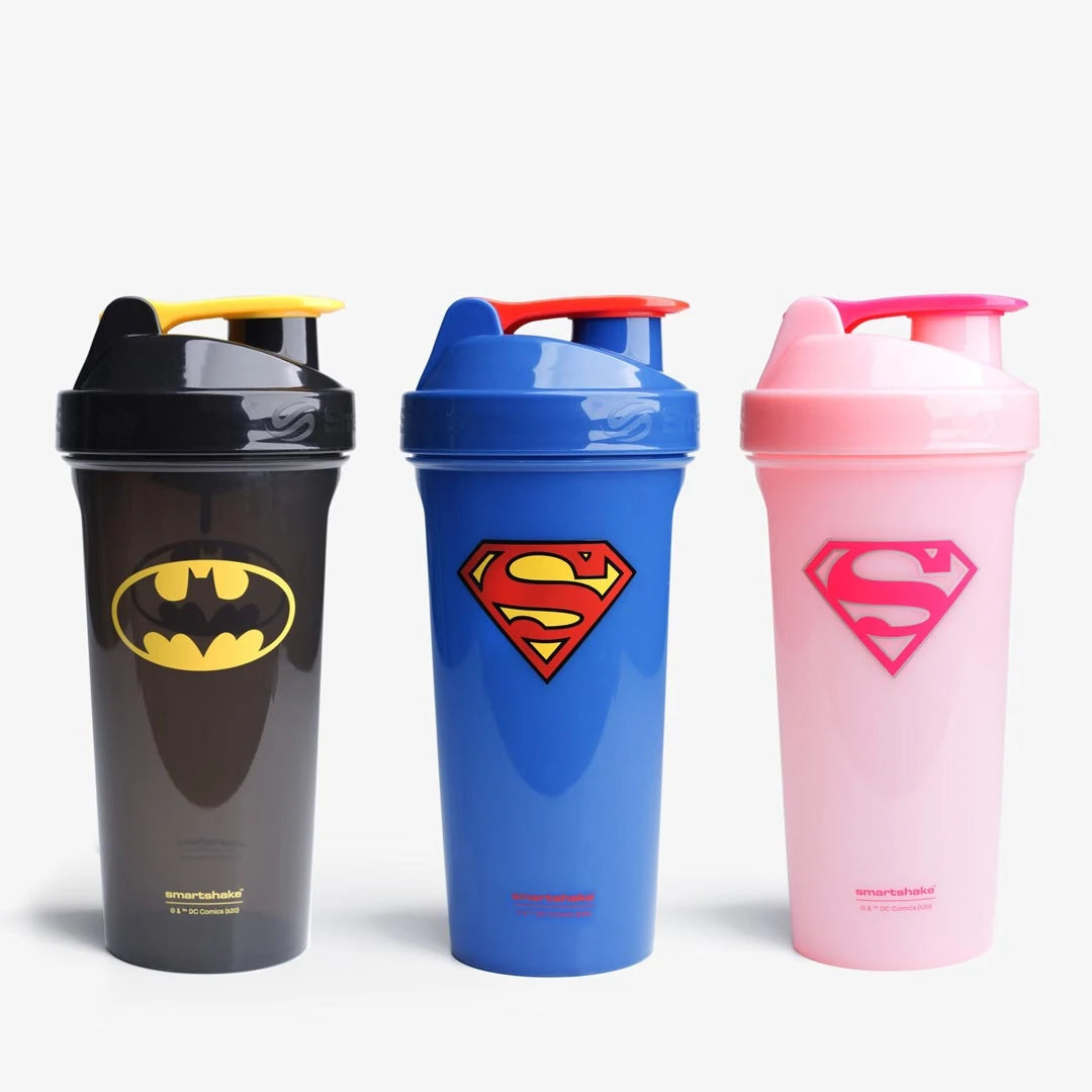 Tre Smartshake Kids 800 ml shakers med superheltmotiv: svart Batman, blå Superman og rosa Supergirl i plast.