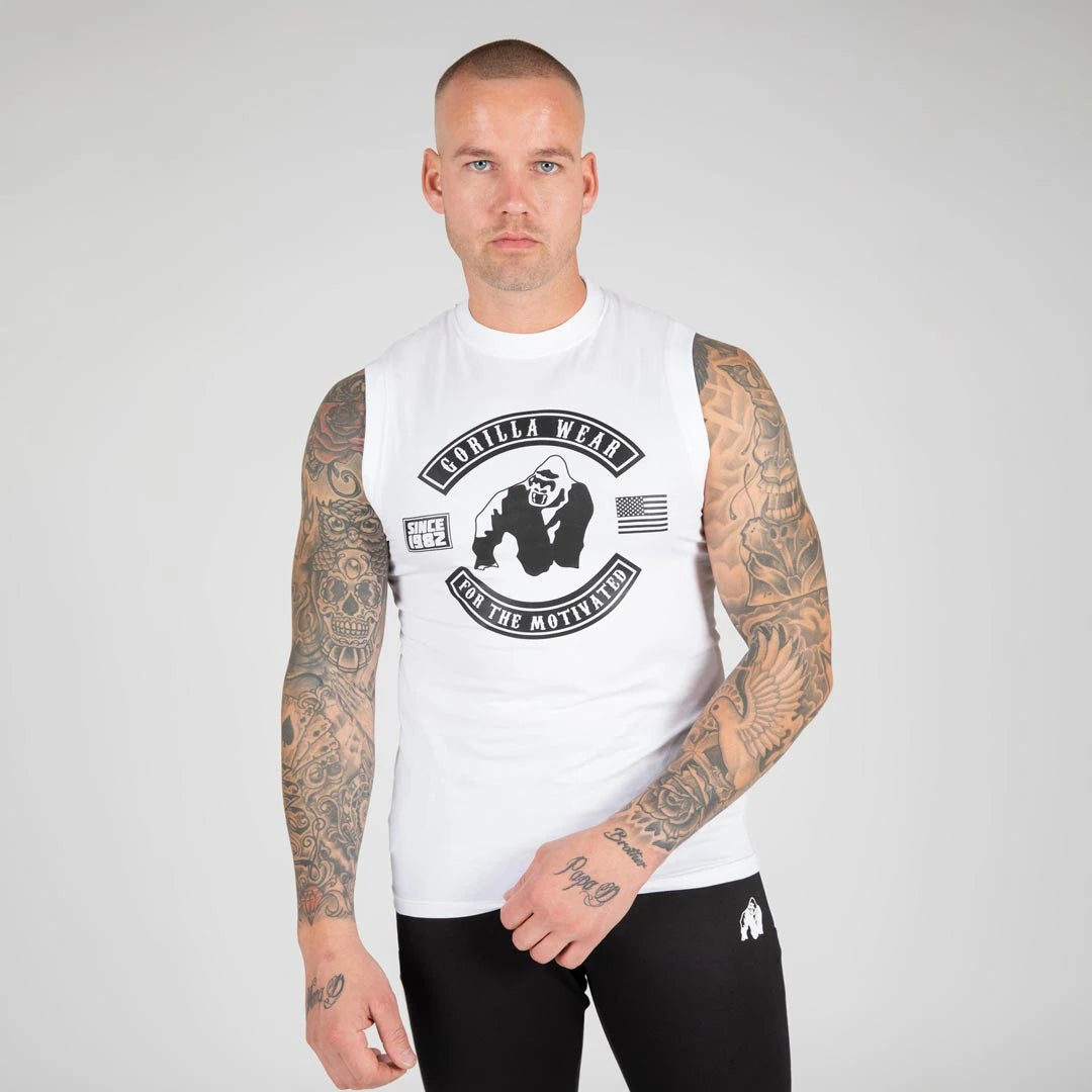 Mann iført Gorilla Wear Tulsa Tank Top White, en hvit treningssinglet i bomull med stort svart trykk på brystet., bilde 4 av 8