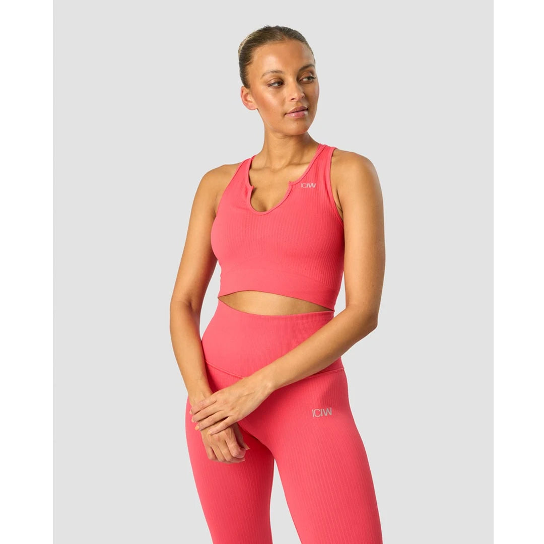 ICANIWILL Ribbed Define Seamless Tank Top Coral Red er en korallrød, ribbet treningstopp båret av en modell.