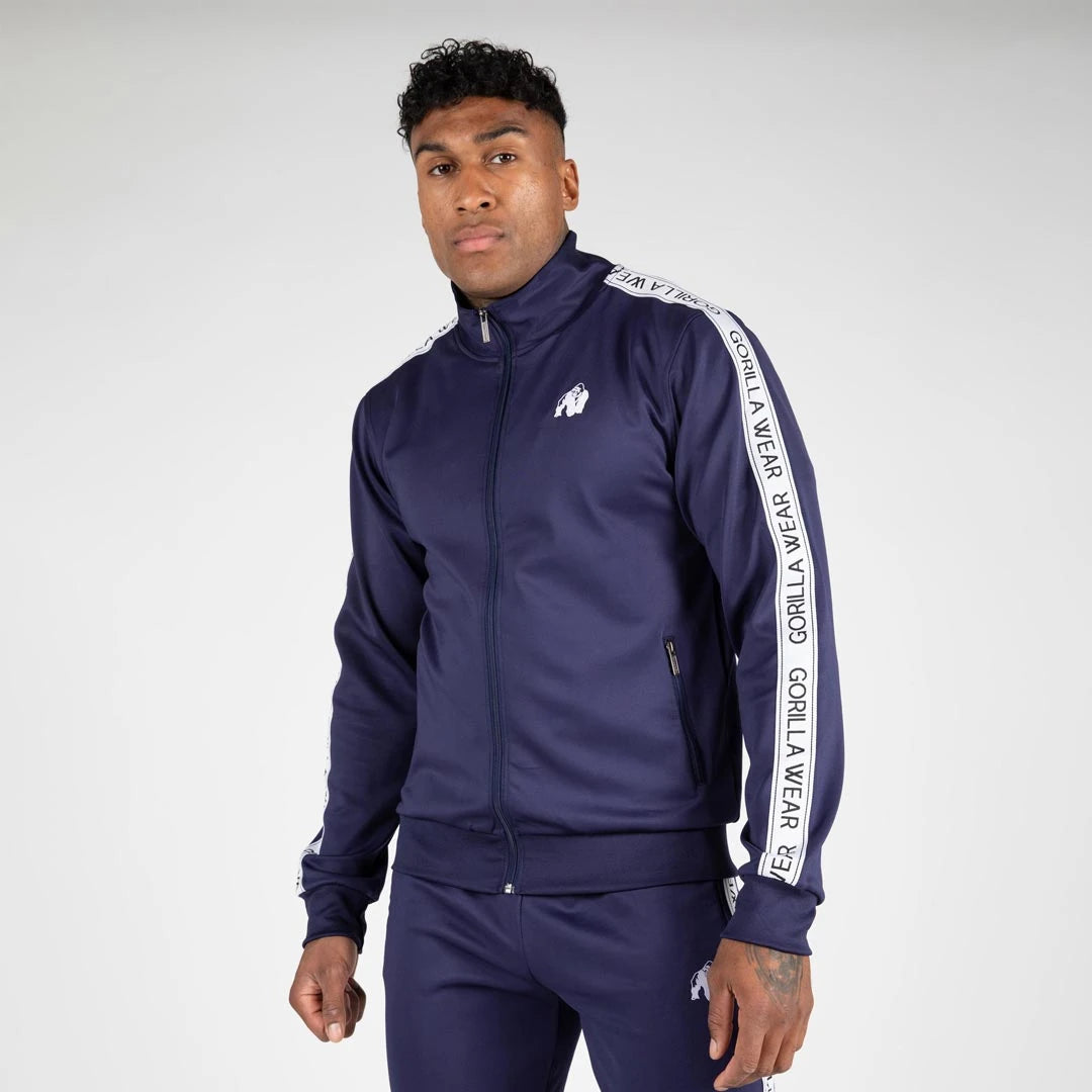 Mann i marineblå Gorilla Wear Delaware Track Jacket navy, en sporty treningsjakke med hvite striper., bilde 2 av 7