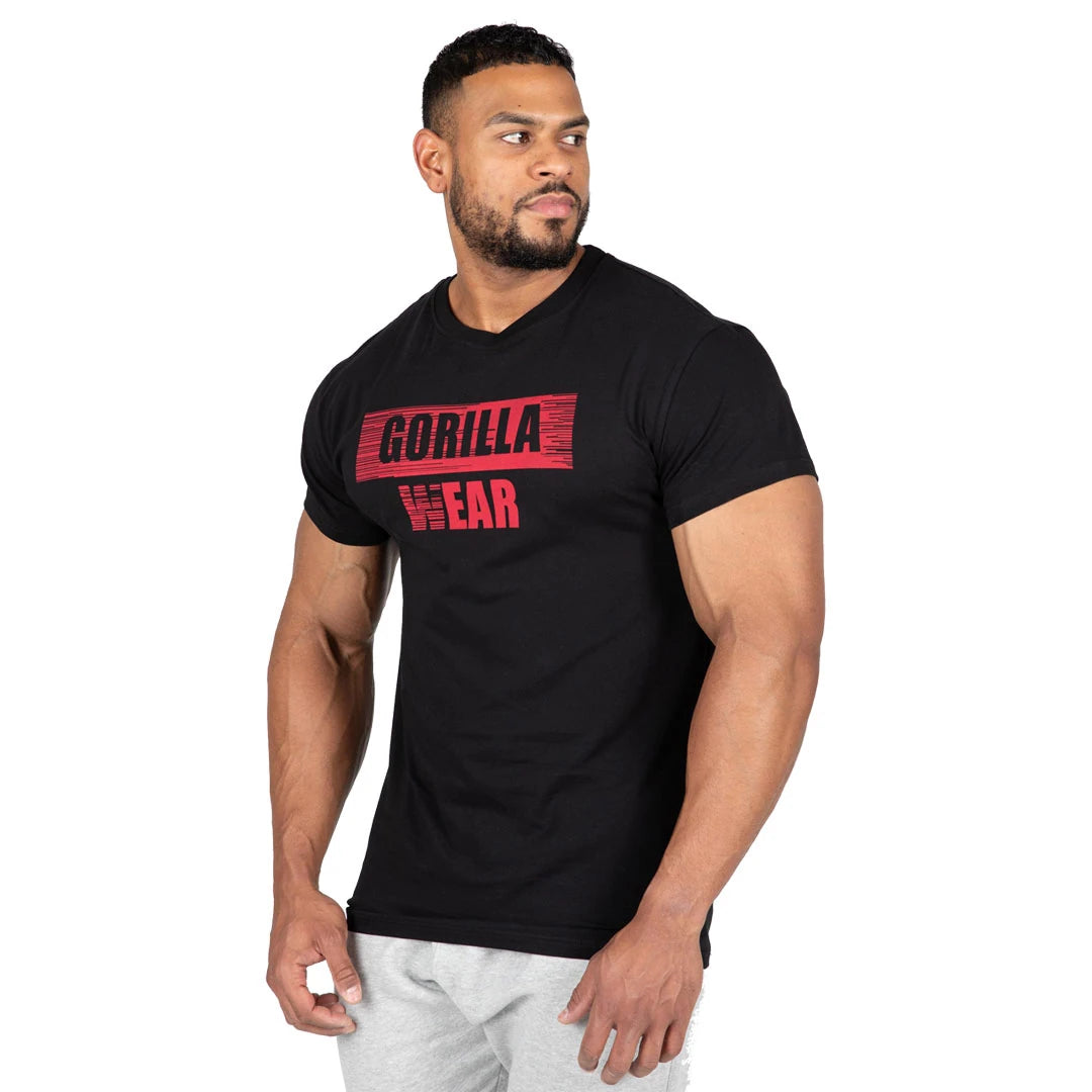 Gorilla Wear Murray T-Shirt Black, en svart slim fit-t-skjorte i bomull med rød brystlogo båret av en mann., bilde 3 av 7