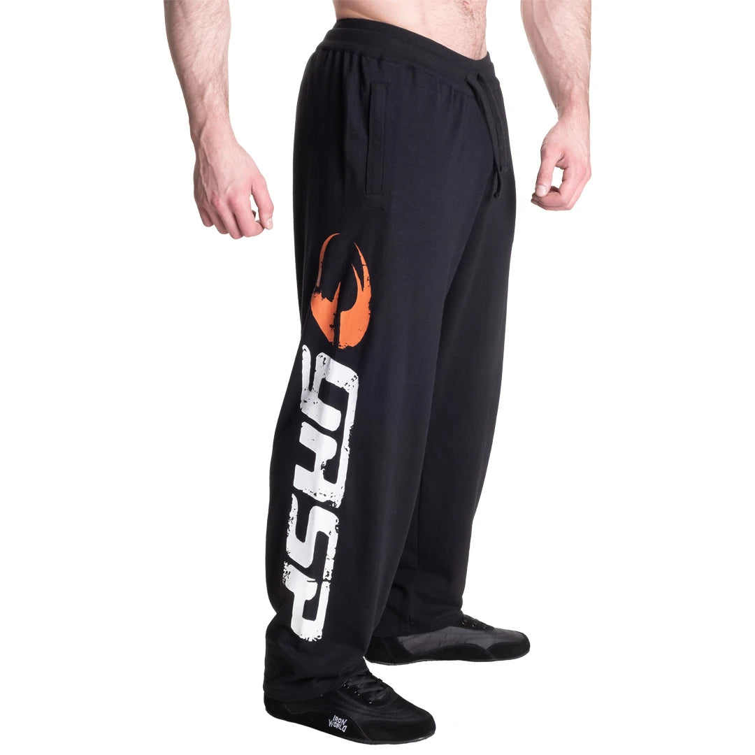 GASP Sweatpants Black/White, svarte treningsbukser med et stort hvitt og oransje logotrykk langs høyre ben.
