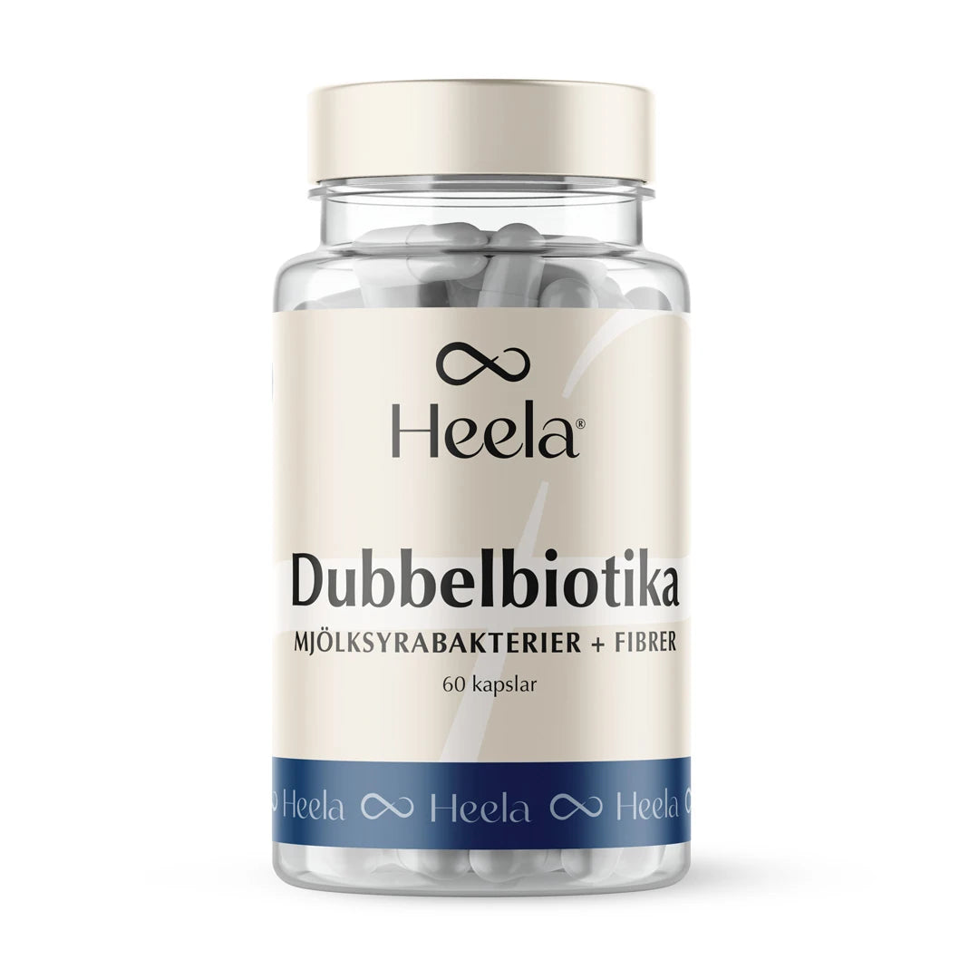 Heela Dubbelbiotika 60 caps i en gjennomsiktig boks med beige etikett, blå detaljer og hvite kapsler inni.
