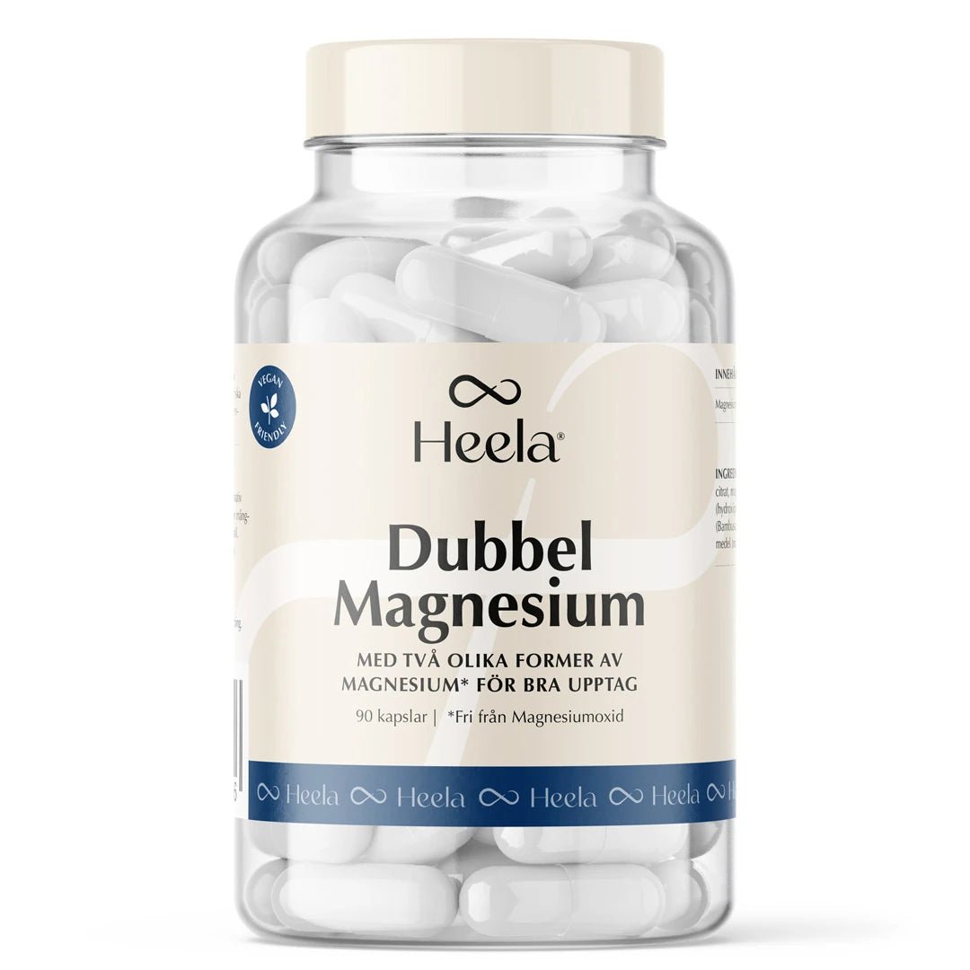 Heela Dubbel Magnesium 90 caps kosttilskudd i en gjennomsiktig boks med lys etikett, fylt med hvite kapsler.