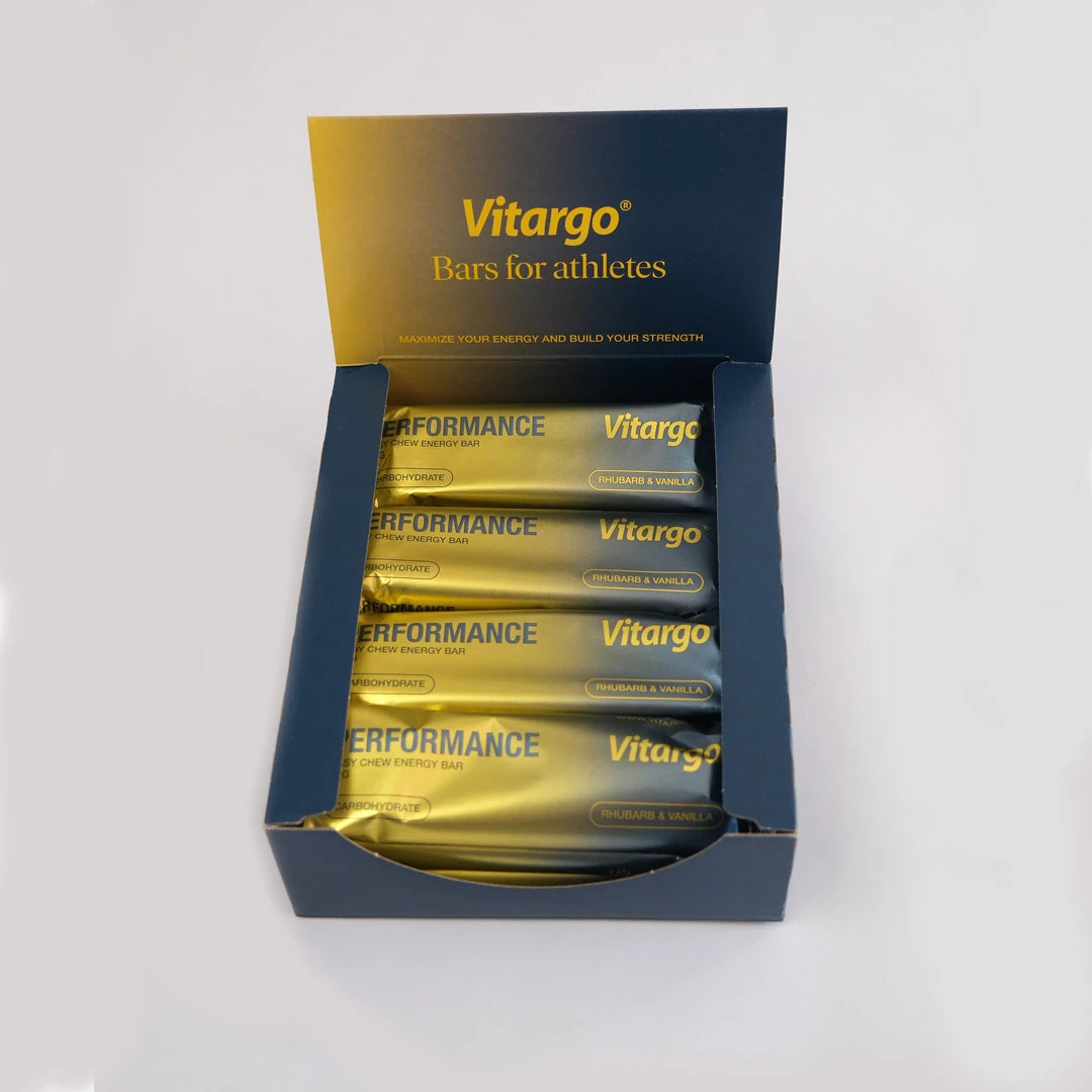 12 x Vitargo Performance Bar 55 g i en mørkeblå eske fylt med gylne energibarer i smaken Rhubarb &amp; Vanilla., bilde 1 av 1