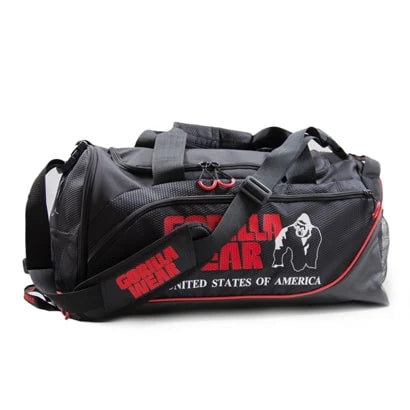 Svart Gorilla Wear Jerome Gym Bag i slitesterk polyester med røde logoer, bærehåndtak og skulderstropp for trening.