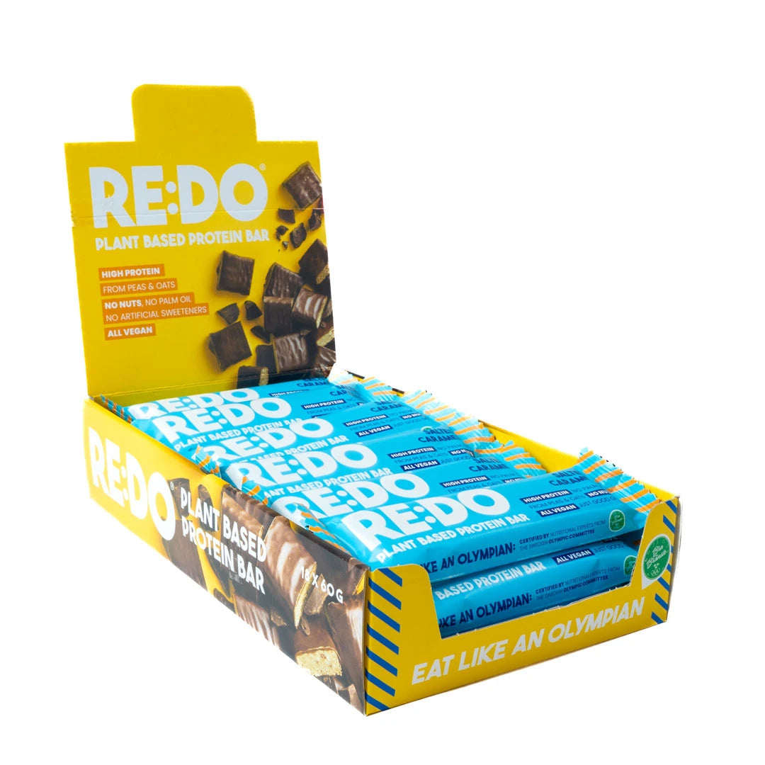 18 x REDO Bar 60 g Salty Caramel i en gul displayeske med blå proteinbarer.