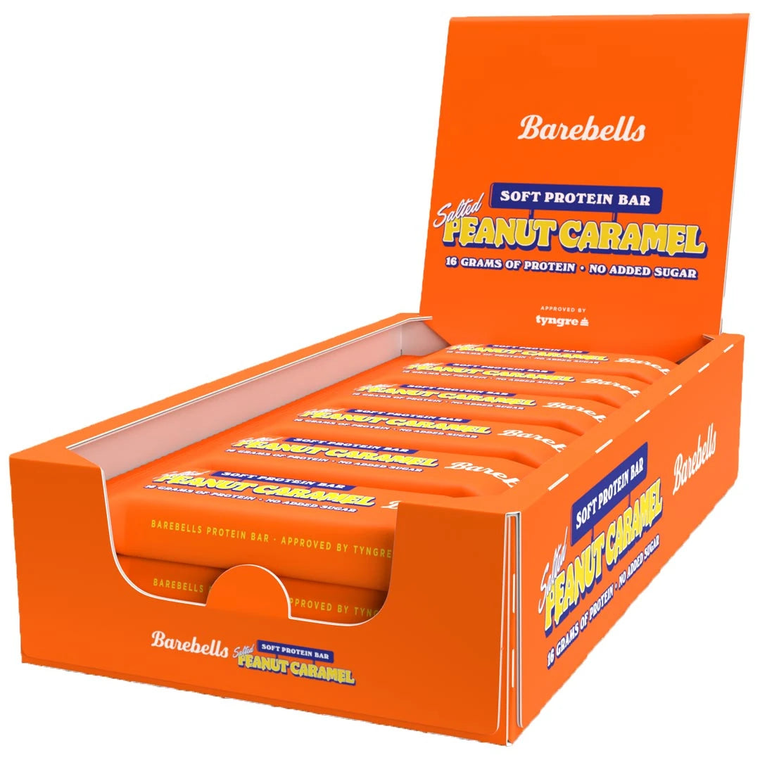 12 x Barebells Soft Protein Bar 55 g Salted Peanut Caramel i en oransje displayboks fylt med matchende barer.