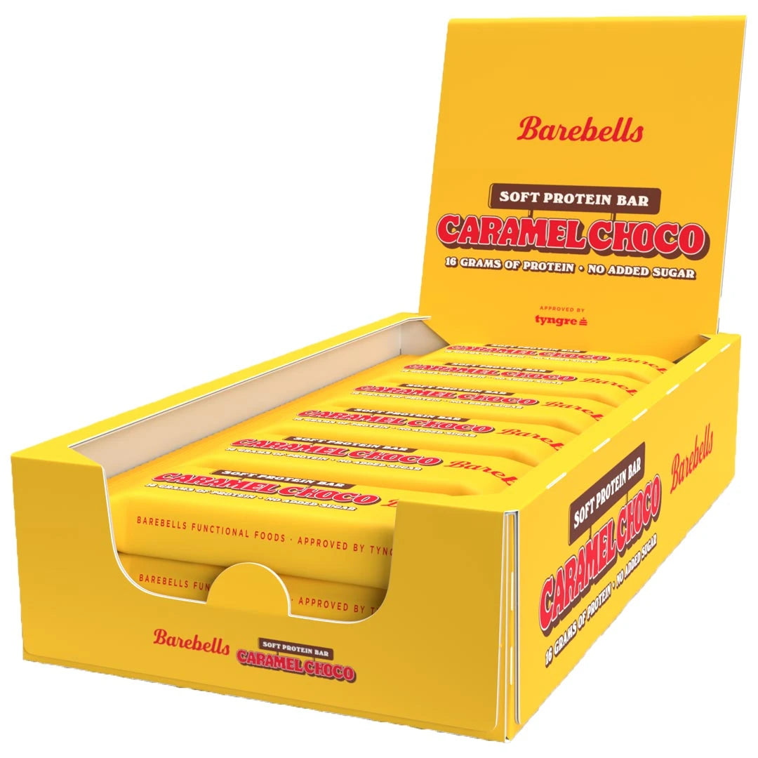12 x Barebells Protein Bar 55 g Caramel Choco i en åpen gul displayeske med røde detaljer.